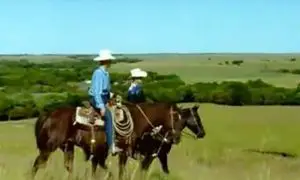 Men on horseback wearing jeans and cowboy hats in the tallgrass prairie