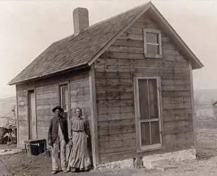section-cabin-family-sepia Sepia-toned image of an African American family outside an antique cabin